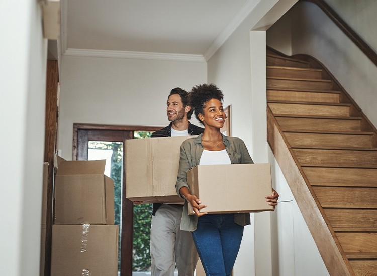 A couple carrying moving boxes into their new home